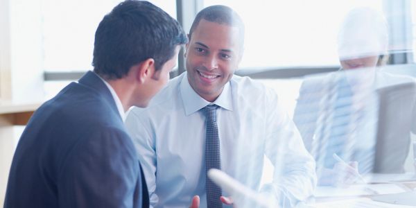Two businessmen in suits having a focused conversation at a meeting table