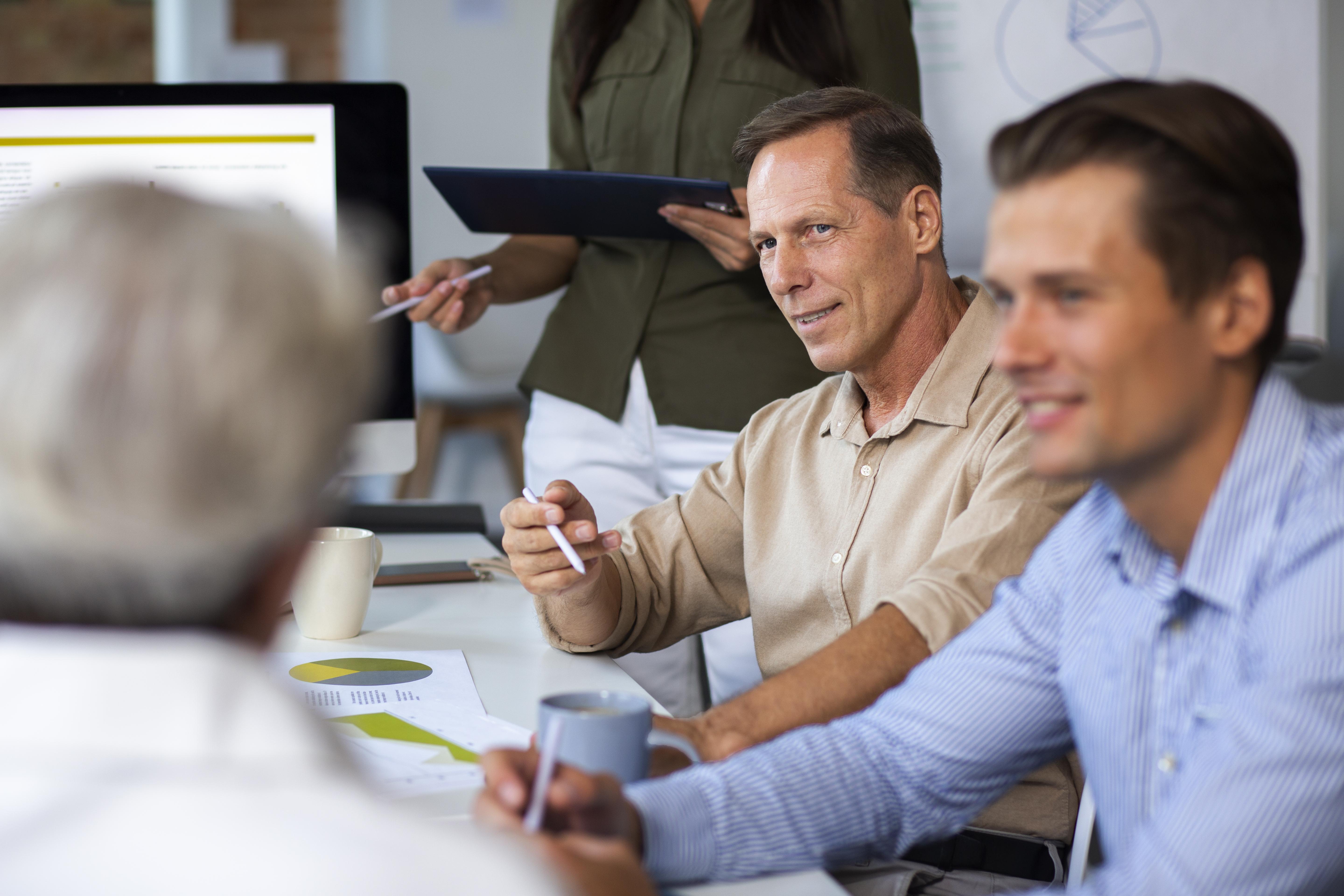 Leadership team in discussion around a conference table with charts and a laptop
